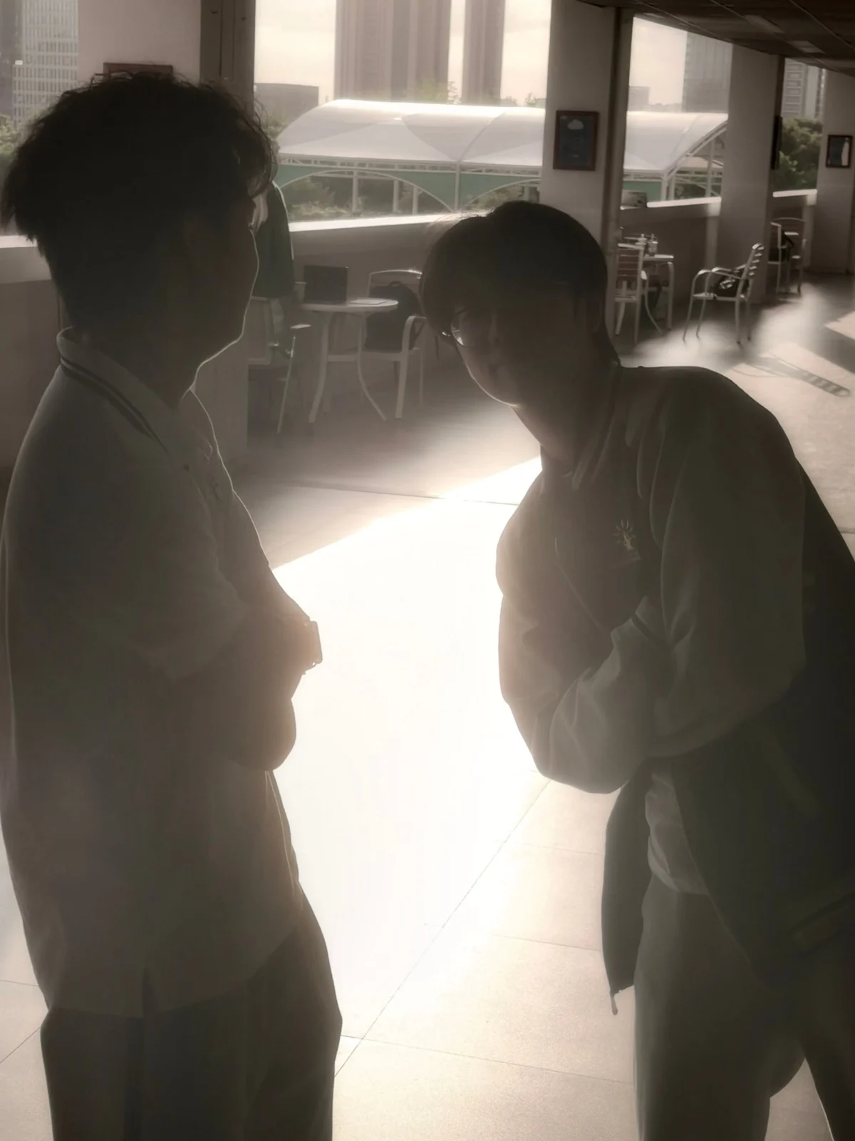 Two friends talking in silhouette against a bright window